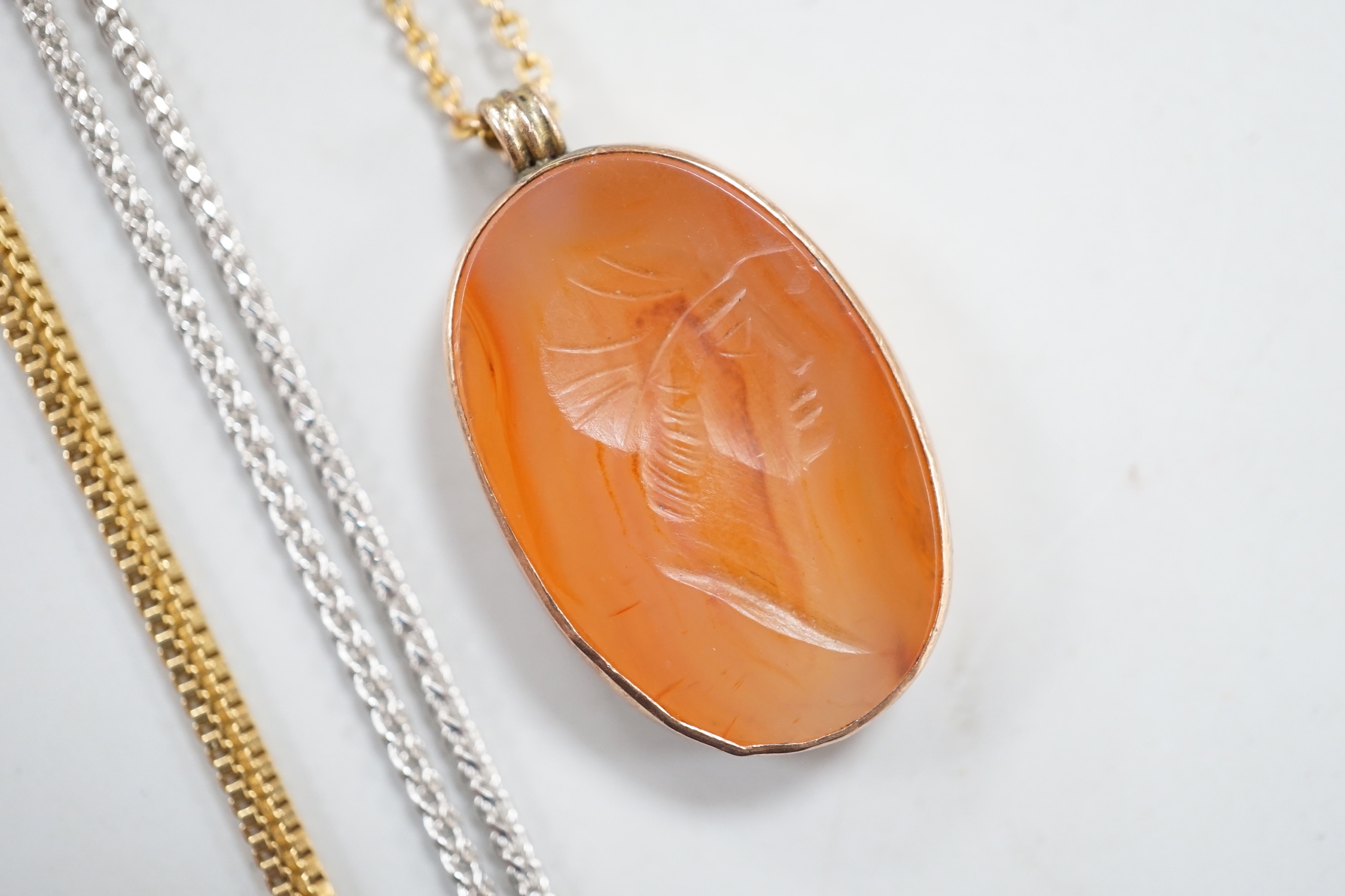 A yellow metal mounted oval intaglio carnelian stone, carved with the bust of gentleman to sinister, 23mm on a 9ct fine link, 37cm and two 9ct gold chains. including white gold, gross weight 8.7 grams.